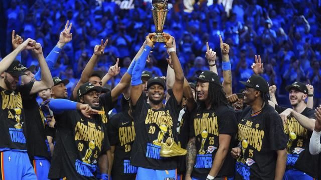 Oklahoma City Thunder guard Shai Gilgeous-Alexander, center, holds up the MVP trophy as he celebrates with his team after they won the NBA basketball championship with a Game 7 victory against the Indiana Pacers Sunday, June 22, 2025, in Oklahoma City. (AP Photo/Julio Cortez)